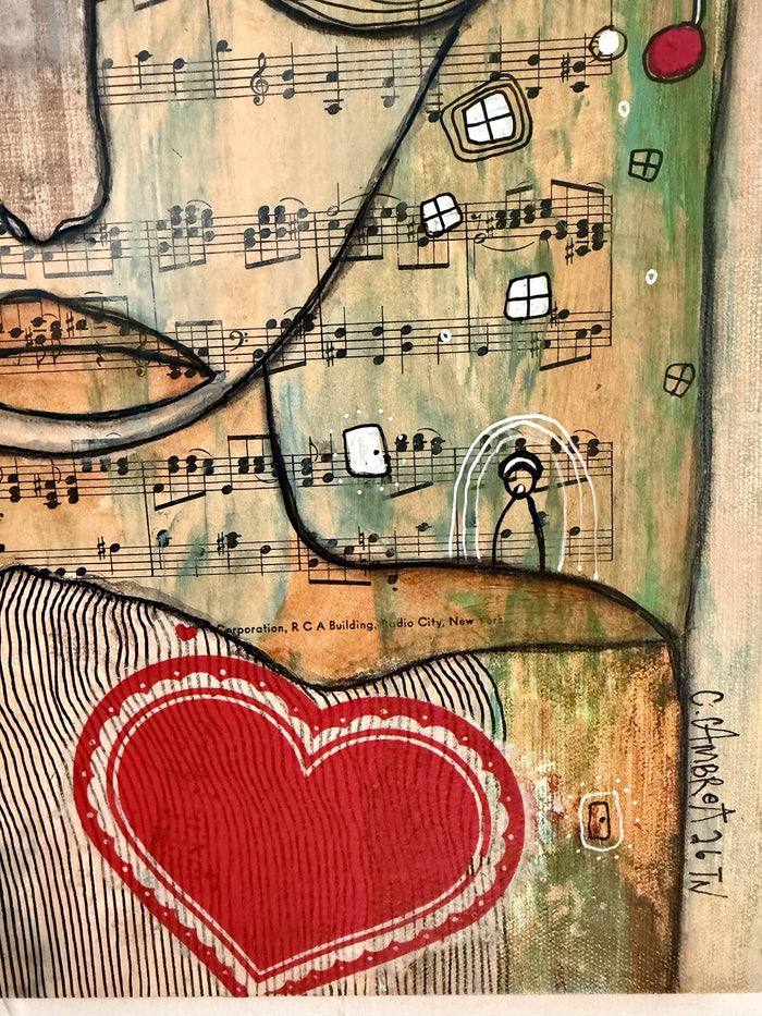 Detail of a red heart on striped fabric with sheet music background and the artist's signature.